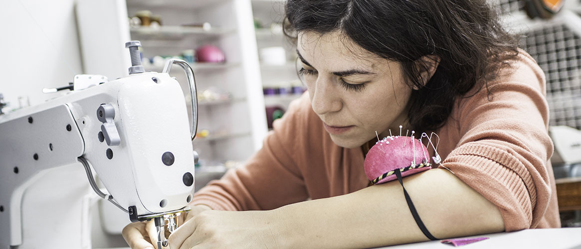 Woman inspecting sewing machine needle for safety in a garment workshop