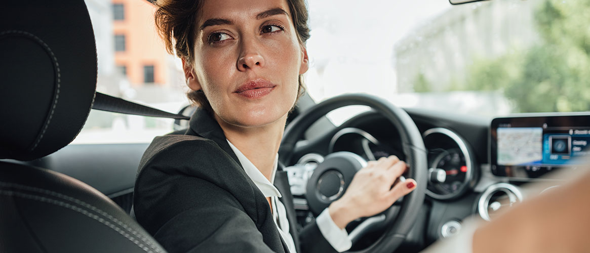 Employee looking through rear window for obstacles while backing up her vehicle