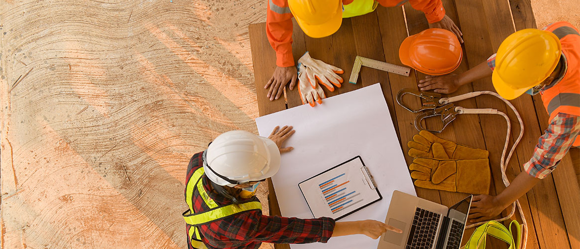 Construction workers discussing use of safety gear in preparation for work Construction workers discussing use of safety gear in preparation for work
