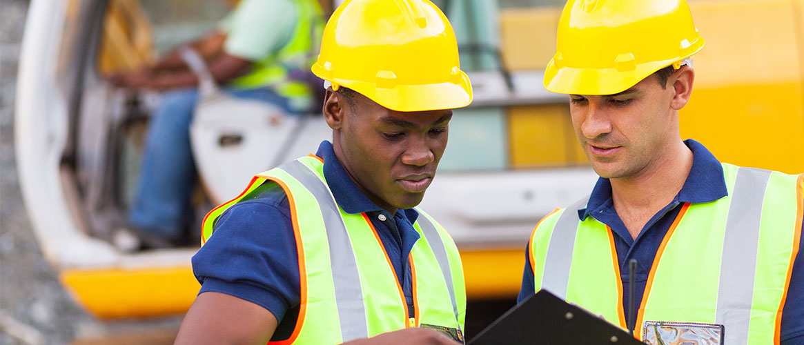Construction workers wearing hard hats discussing their job duties