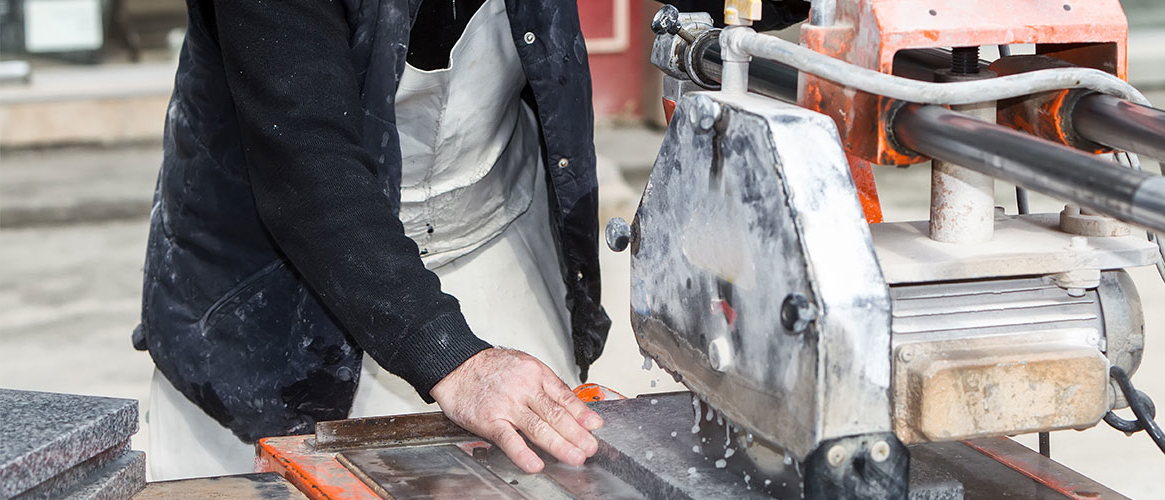 Worker cutting marble using a wet method to minimize silica exposure