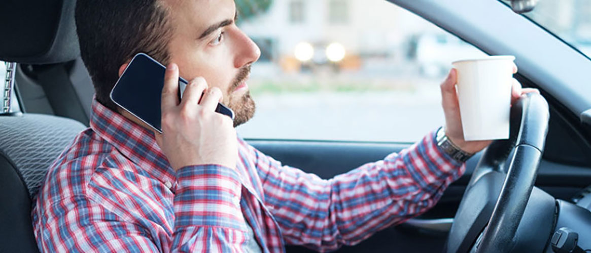 Man driving distracted with mobile phone and coffee